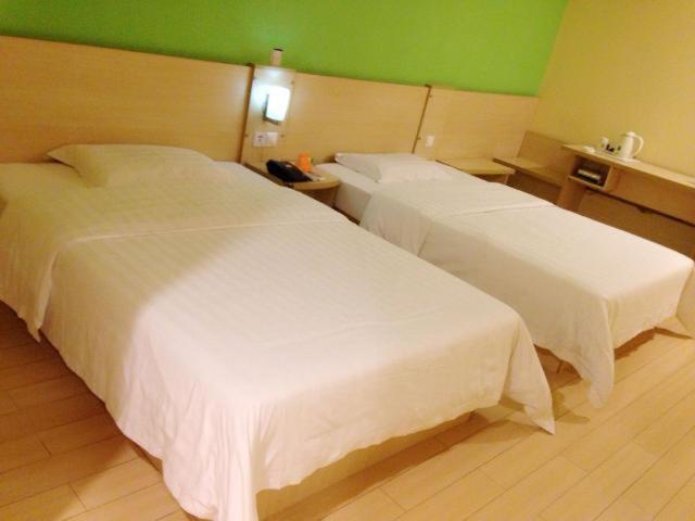 a hotel room with two beds and a green wall at 7Days Inn Suzhou Park New Area Commercial Street in Suzhou