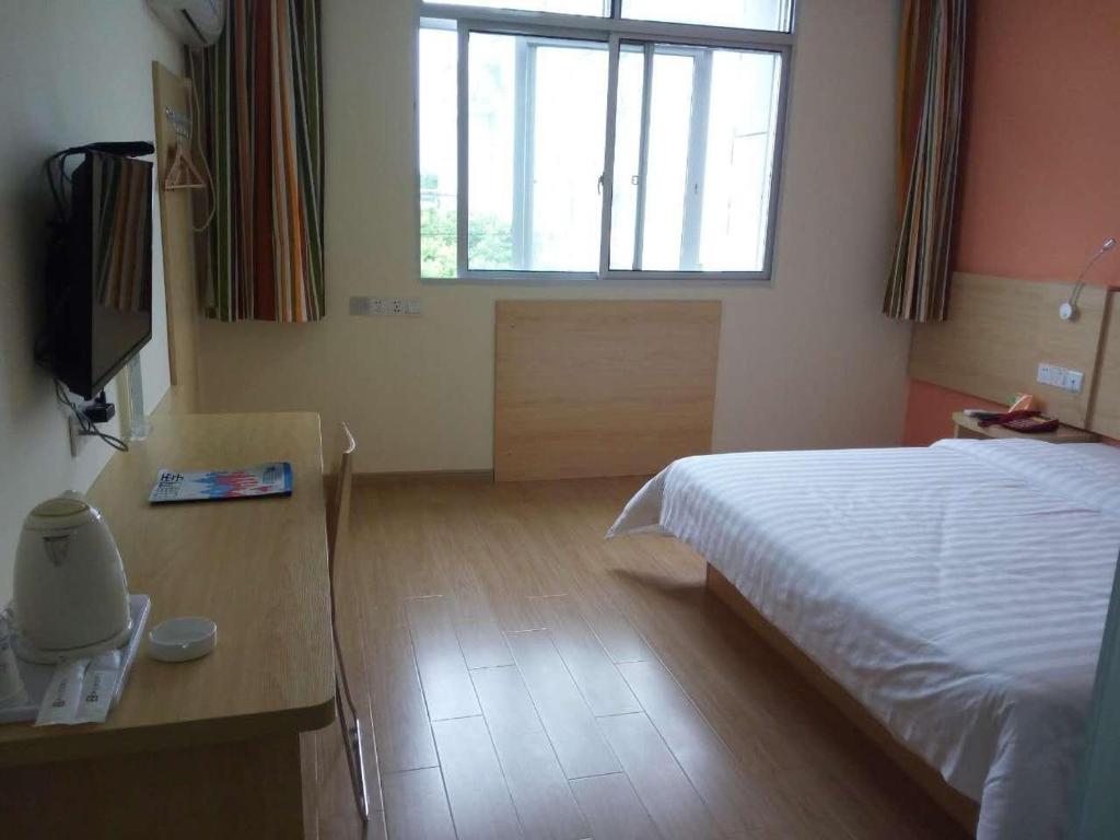 sypialnia z łóżkiem, stołem i oknem w obiekcie 7Days Inn Shangrao Wannian Pharmaceutical Company Store w mieście Wannian