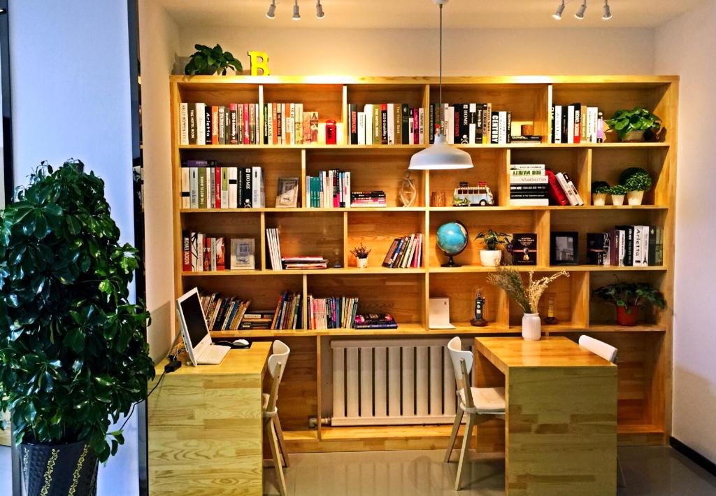 una habitación con una mesa y una estantería con libros en 7Days Premium Dalian Development Zone Wucaicheng rail station, en Dalian
