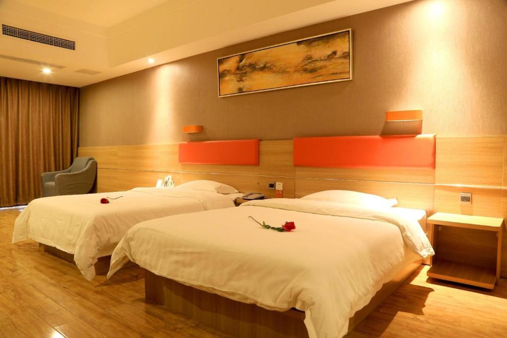 a hotel room with two beds with roses on them at 7Days Premium Neijiang Wanda Square in Neijiang