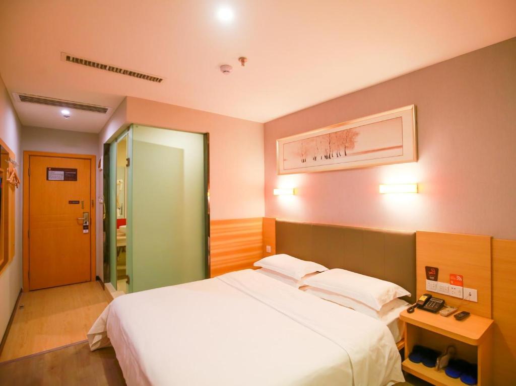 een slaapkamer met een groot wit bed en een spiegel bij 7Days Premium Zhangjiajie Railway Station Square in Zhangjiajie