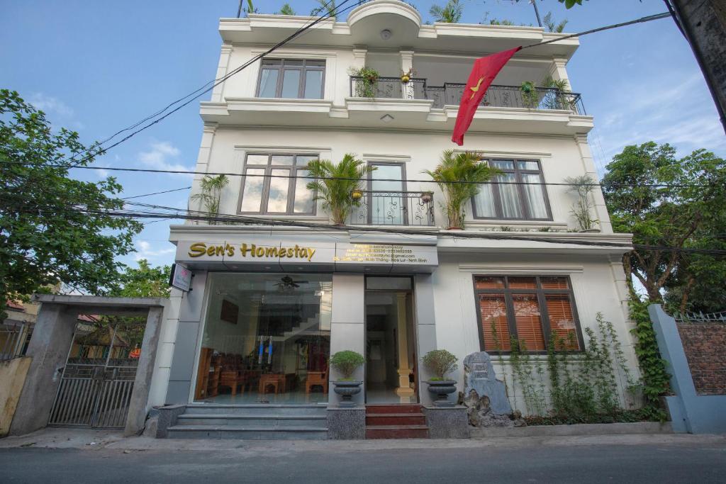 a white building with a red flag in front of it at Sen's Homestay in Ninh Binh