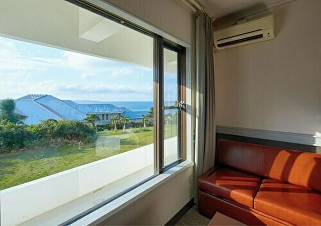 a couch in a room with a large window at Royal View Hotel Churaumi in Motobu