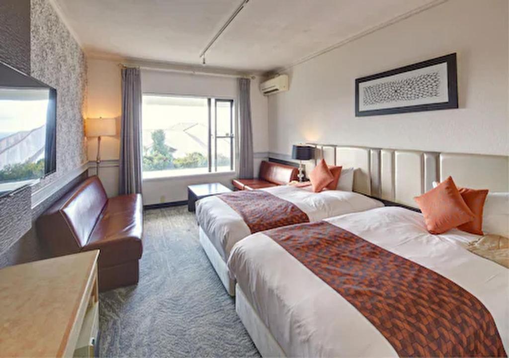 a hotel room with two beds and a flat screen tv at Royal View Hotel Churaumi in Motobu