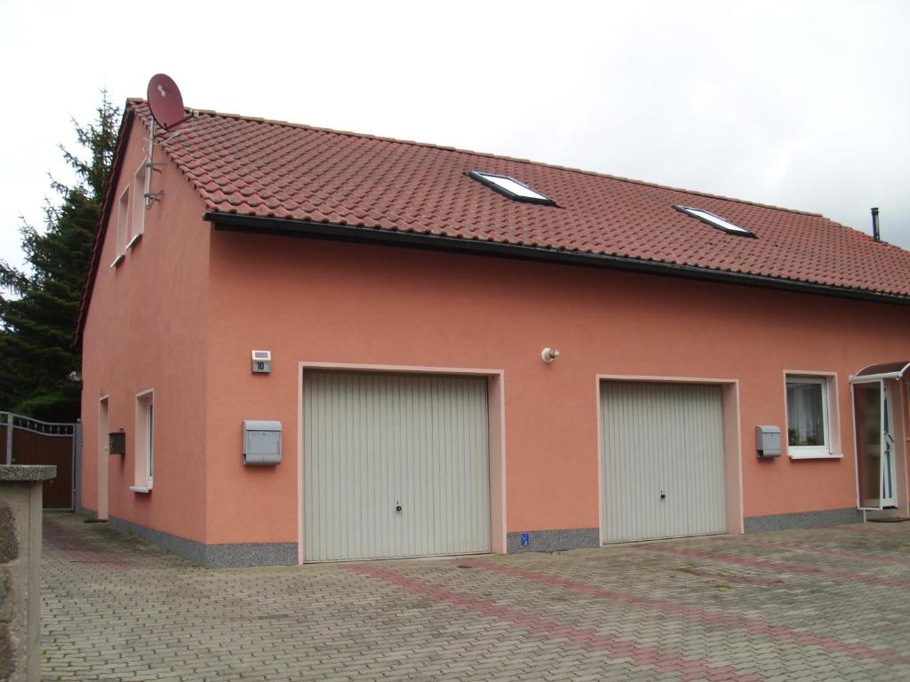 un edificio rojo con tres puertas de garaje. en Ferienwohnung Am Dorfplatz, en Lutherstadt Wittenberg