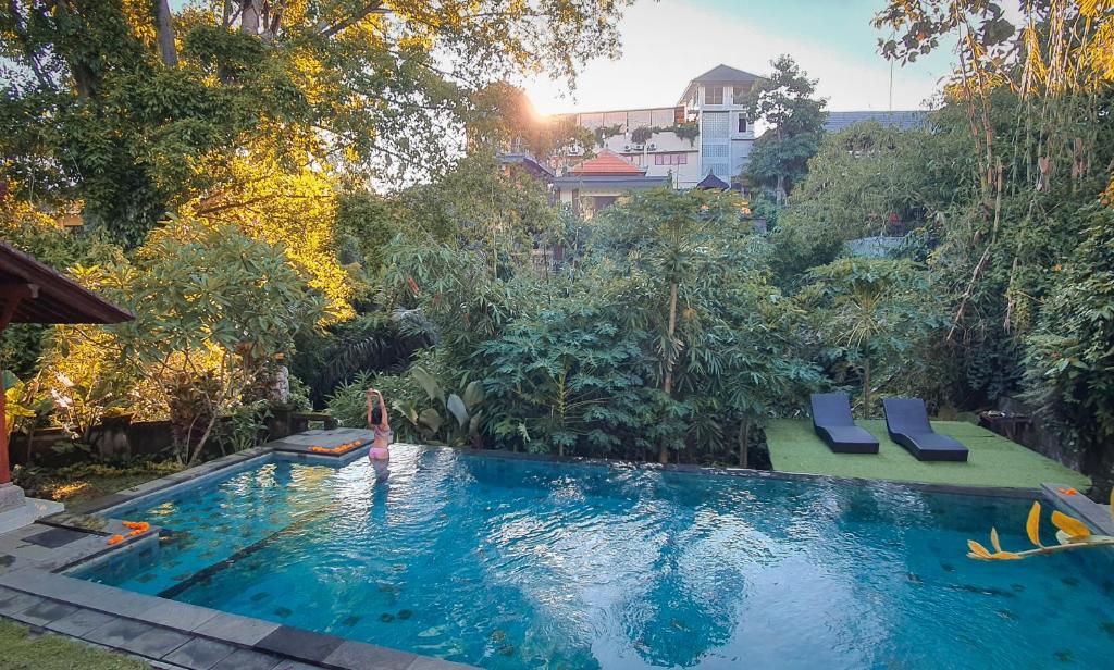 a woman standing in a swimming pool in a backyard at Yuliati House in Ubud