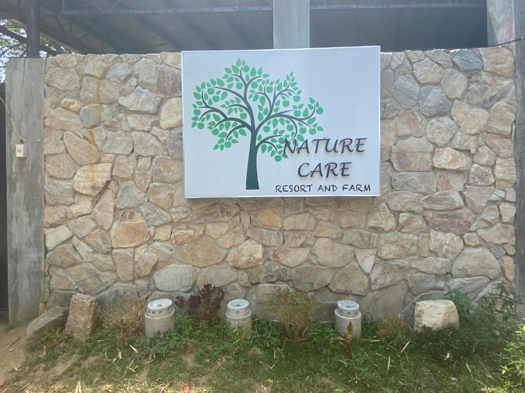 Nature Care Resort and Farm في Pulilan: علامة على جدار حجري مع علامة للعناية anature