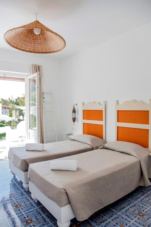 two beds in a white bedroom with a chandelier at Mari del Sud Resort in Vulcano