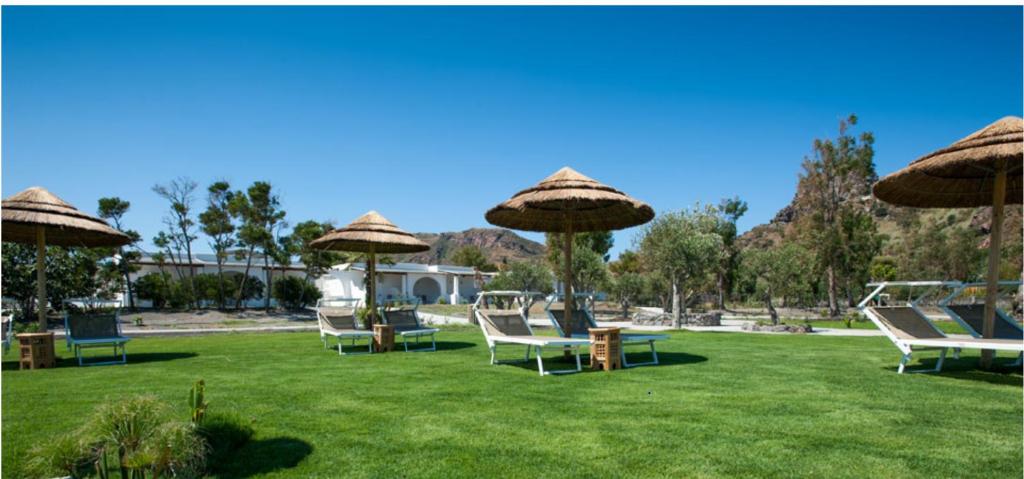 a group of chairs and umbrellas on a lawn at Mari del Sud Resort in Vulcano