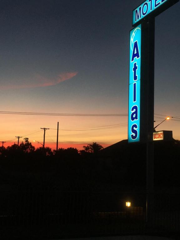 a sign for a motel with the sunset in the background at Atlas Motel in Dubbo