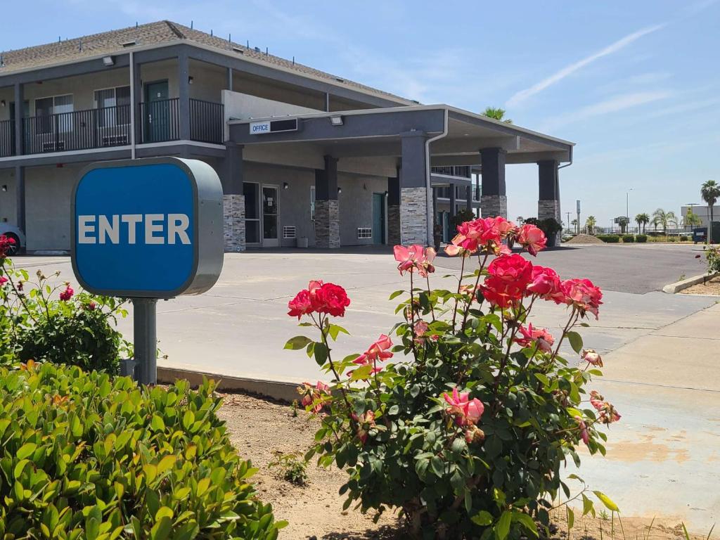 a enter sign in front of a building with flowers at SureStay Hotel by Best Western Chowchilla Yosemite in Chowchilla