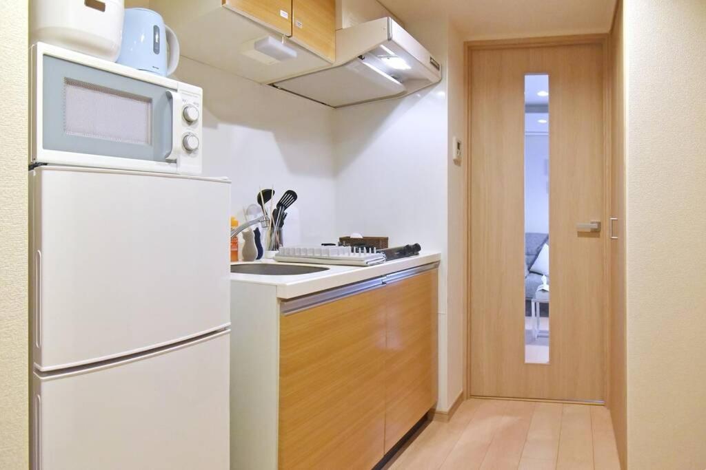 a kitchen with a white refrigerator and a microwave at IDstay大森301 in Tokyo