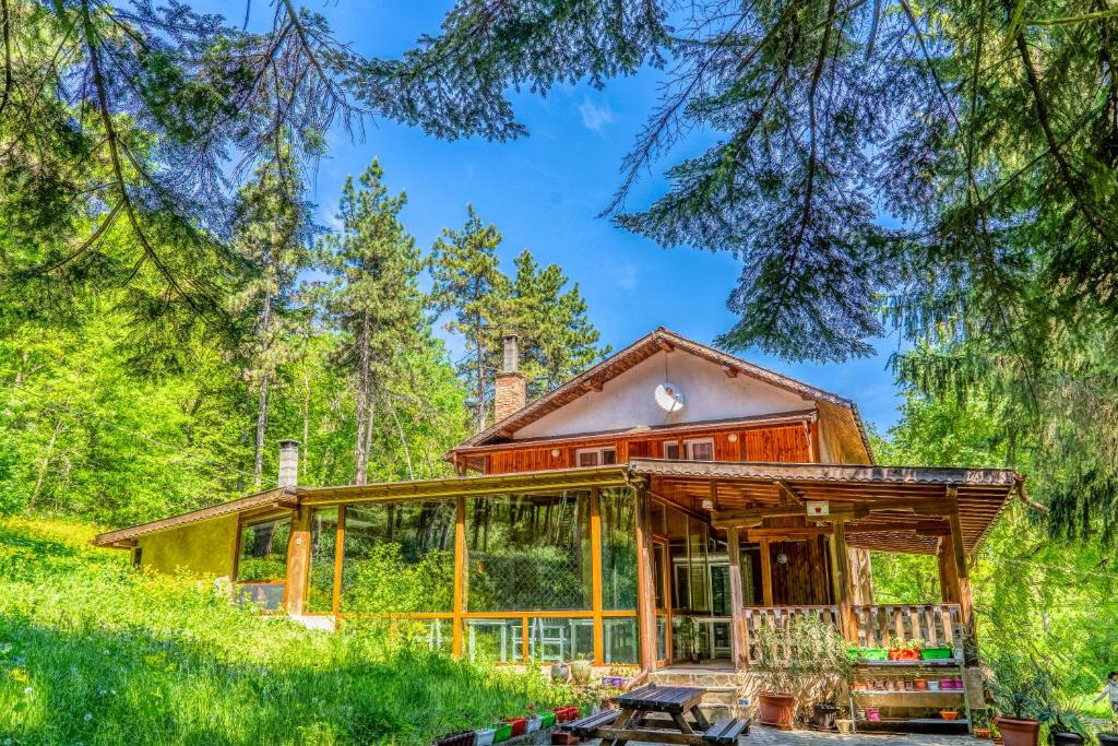 ein Haus im Wald mit einer großen umlaufenden Veranda in der Unterkunft Къща за гости - Крушун in Krushuna