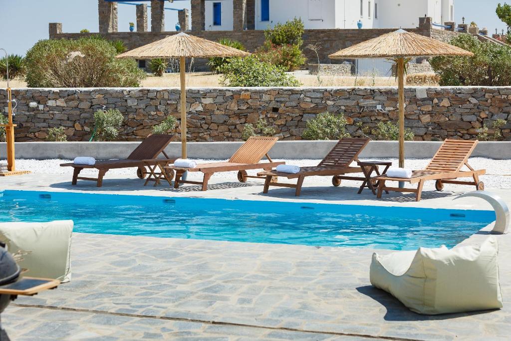 a swimming pool with chairs and umbrellas next to a pool at Punda Villas Paros in Kampos Paros