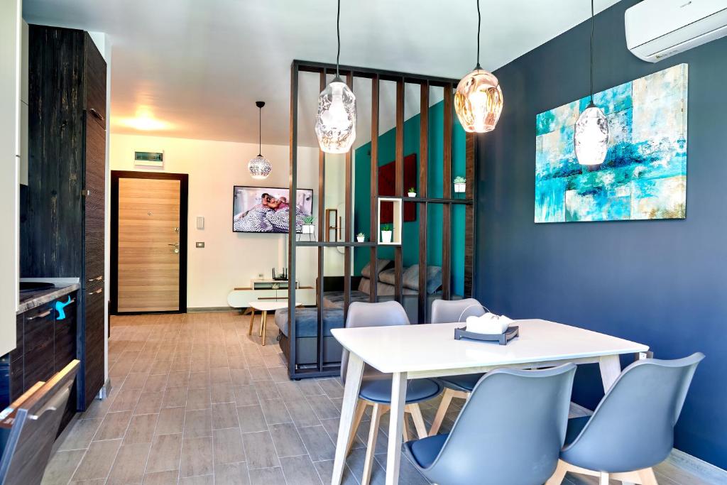 une salle à manger avec une table blanche et des chaises bleues dans l'établissement Rusty Sands apt Spa n Pools Beach resort, à Mamaia Nord – Năvodari