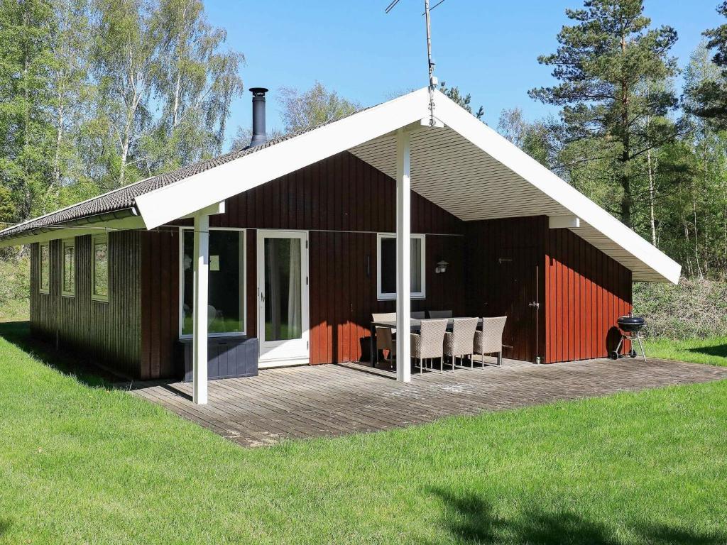 a building with a deck with a table and chairs at 4 person holiday home in L s in Læsø