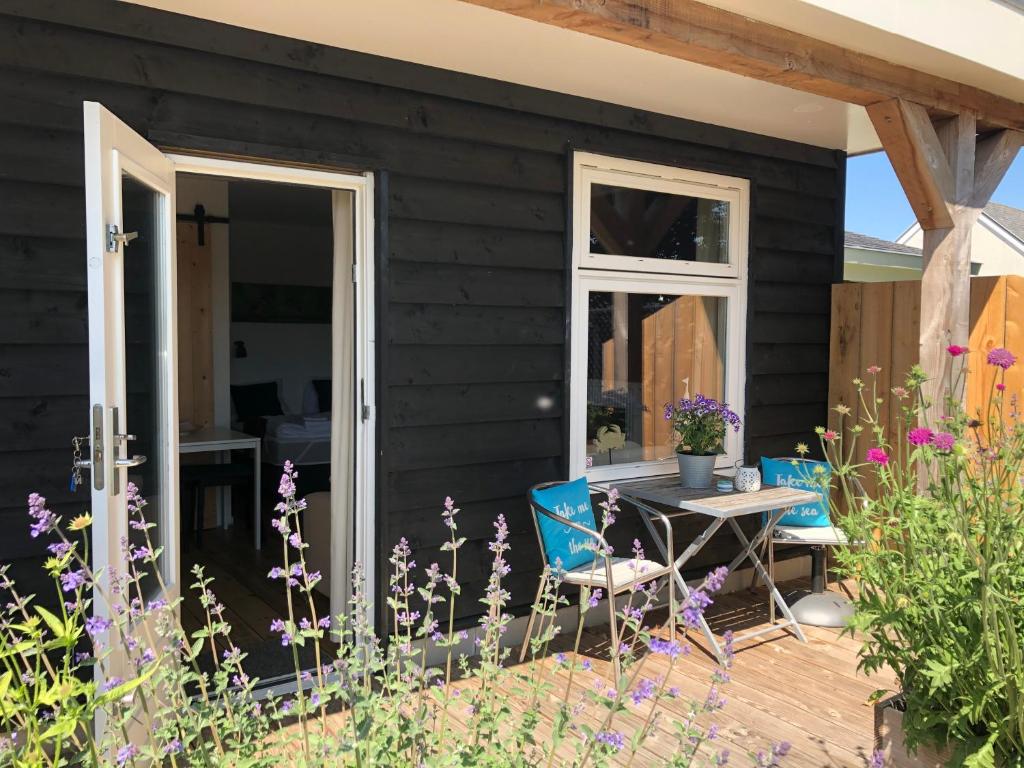 a black house with a table and chairs on a deck at Studio appartement 1nul9Noord in Renesse
