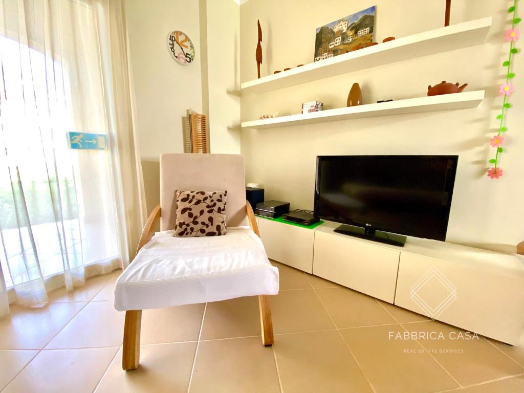uma sala de estar com uma cadeira e uma televisão de ecrã plano em Cozy Family 3 BR apartment by the sea em Marsa Alam
