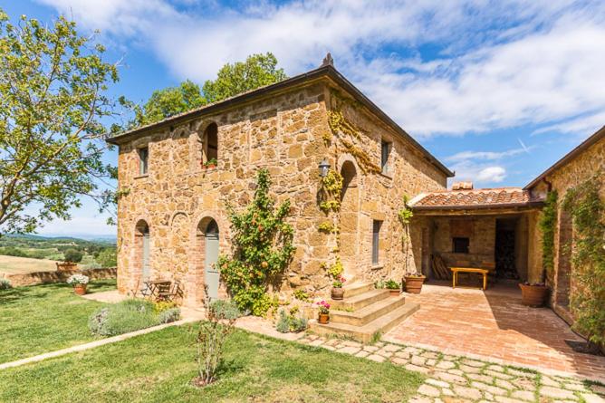 ein großes Steingebäude mit einer Veranda und einer Terrasse in der Unterkunft Casale Santa Barbara in Montefollonico
