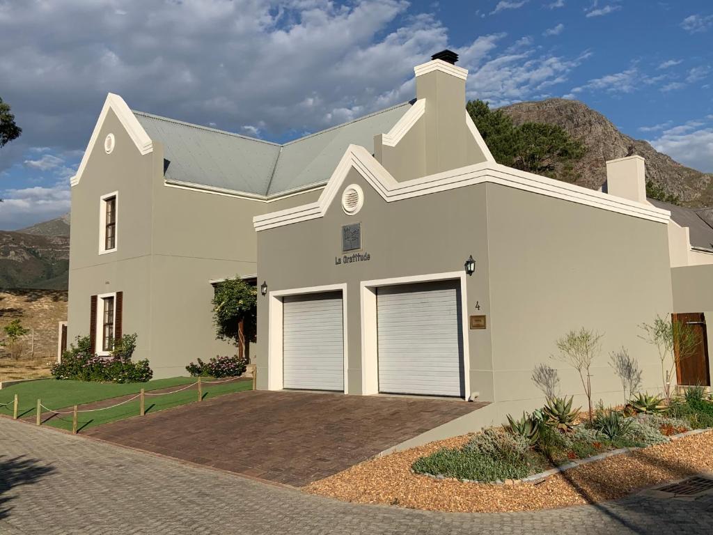 a white house with two garage doors at La Gratitude Self catering cottage in Franschhoek