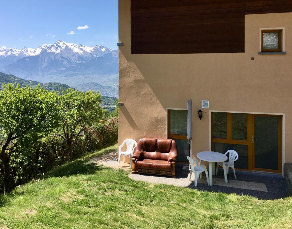 a house with a chair and a table and mountains at La Chaumière d'Hérens in Vernamiège