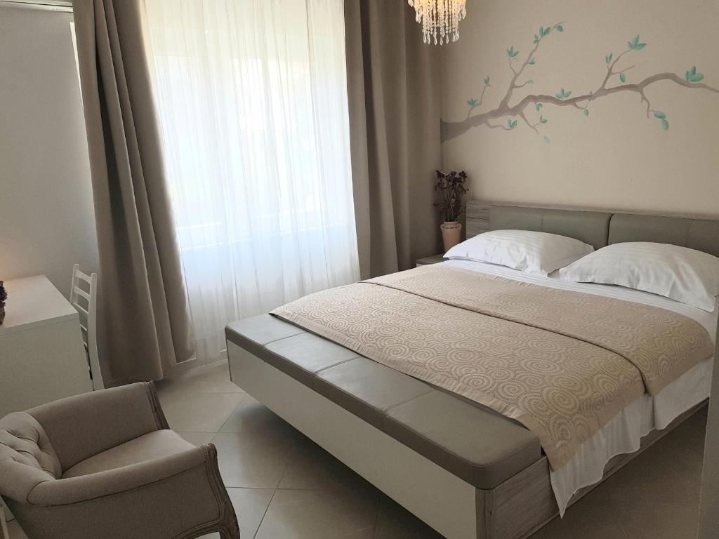 a bedroom with a bed and a chair and a tree mural at Boutique Villa Revelin in Pag