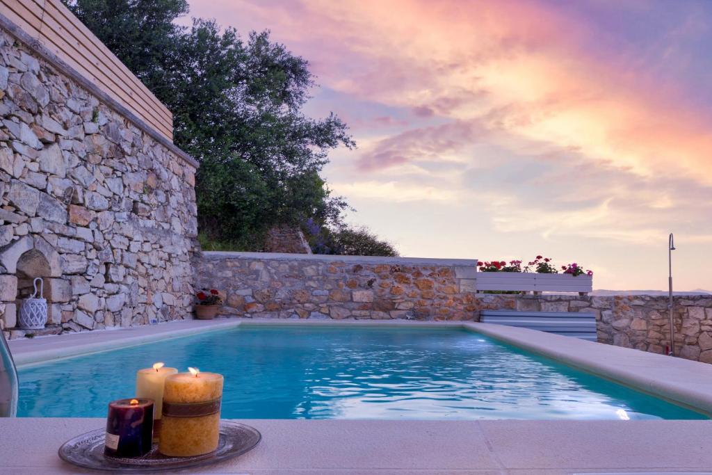 MakhairoíにあるOlga's Filoxenia - Villa Aladanos-private pool and heated jacuzziのキャンドル2本と石壁のスイミングプール