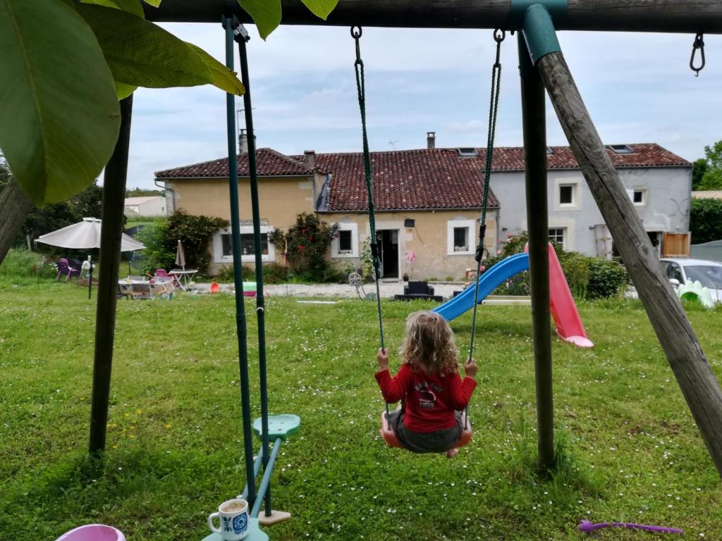 uma menina sentada num baloiço no quintal em Les Marmottes Charentaises em Tonnay-Boutonne