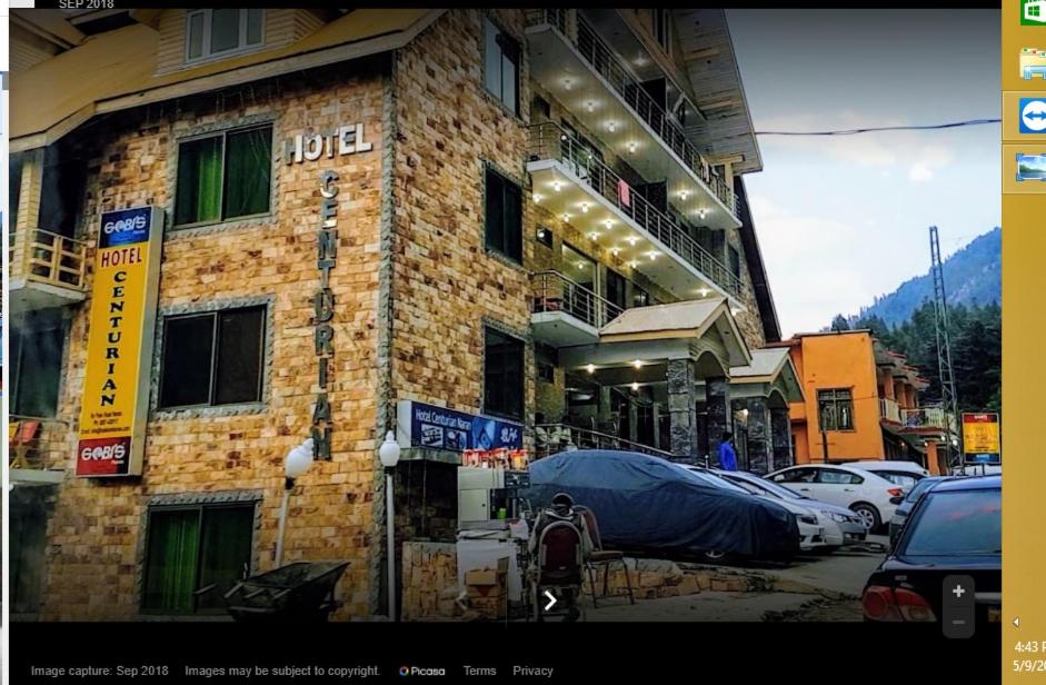 un edificio de ladrillo con coches estacionados frente a él en Centurion Hotel, en Naran