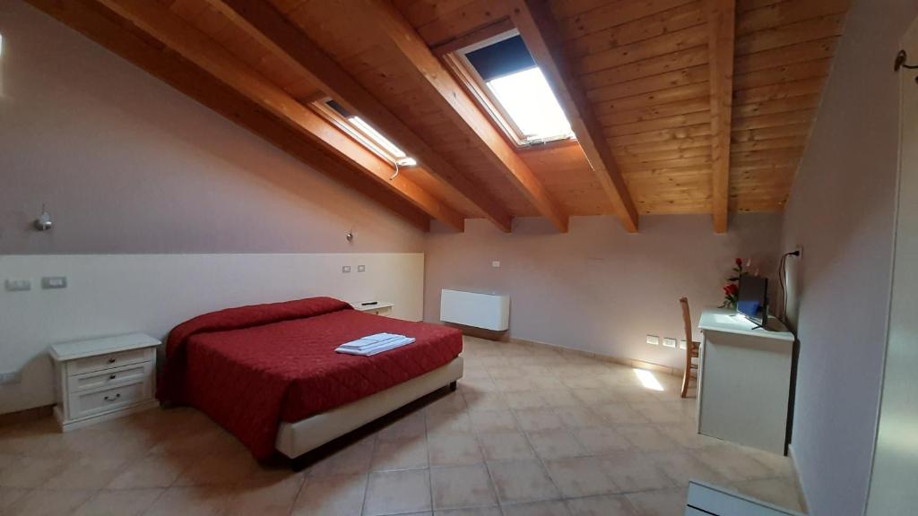 a large bedroom with a red bed and a window at Hotel La Cascina in Fontanellato