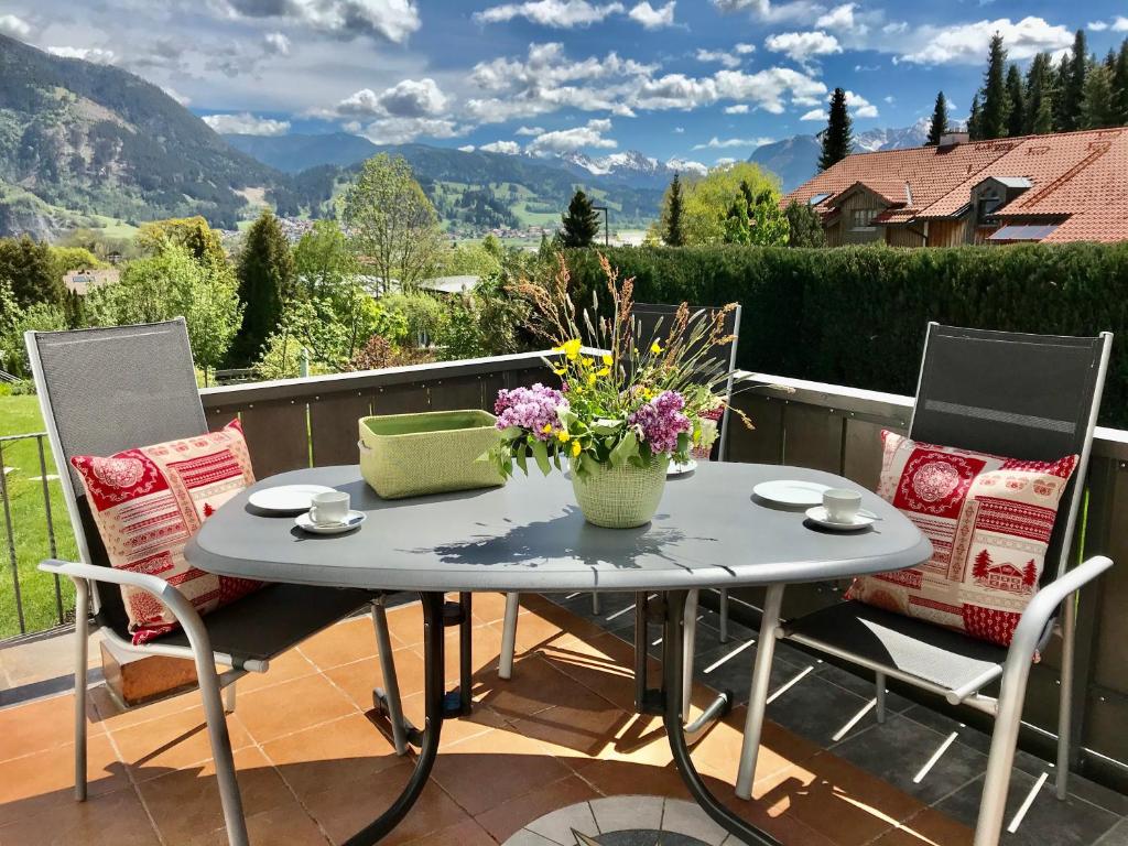 Una mesa con un jarrón de flores en un patio. en Ferienhaus Mang, en Blaichach