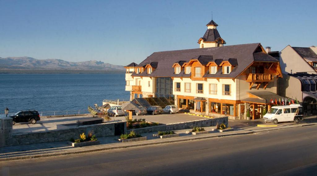 a large house on a beach next to a body of water at Cacique Inacayal Lake Hotel & Spa in San Carlos de Bariloche