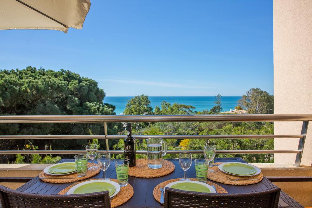 einen Tisch mit Gläsern und eine Flasche Wein auf dem Balkon in der Unterkunft Beach front apartment Barracuda Albufeira in Albufeira