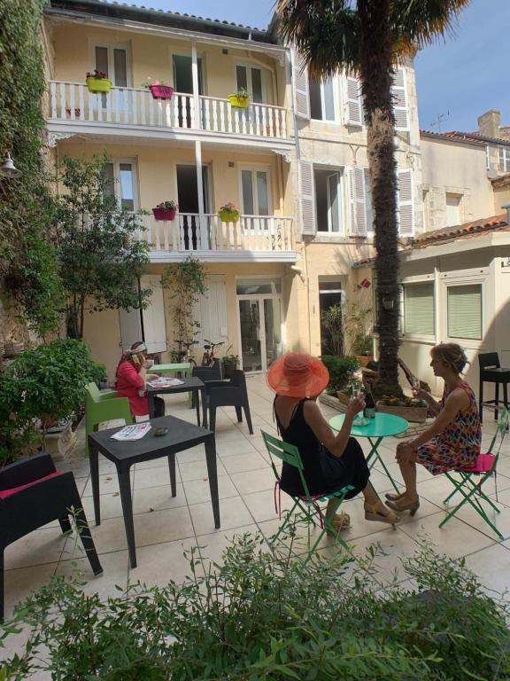 a group of people sitting at tables on a patio at The Originals Boutique, Hôtel Roca-Fortis, Rochefort in Rochefort