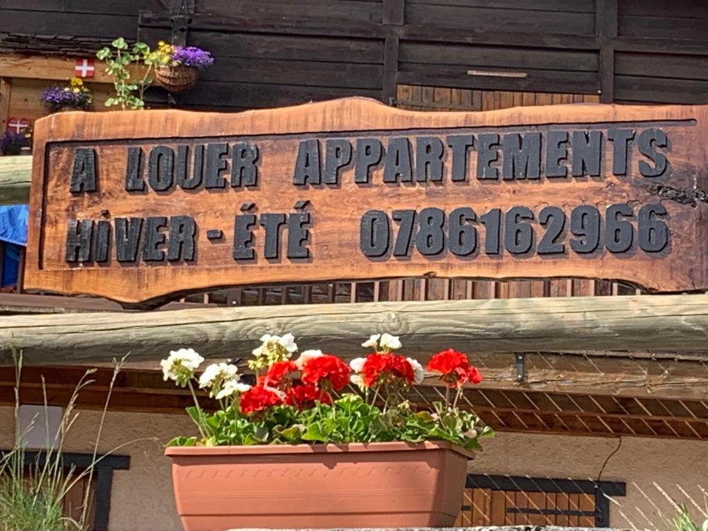 a sign on a building with flowers in a pot at APPARTEMENT PLEIN SUD AUX SAISIES N°6 in Les Saisies