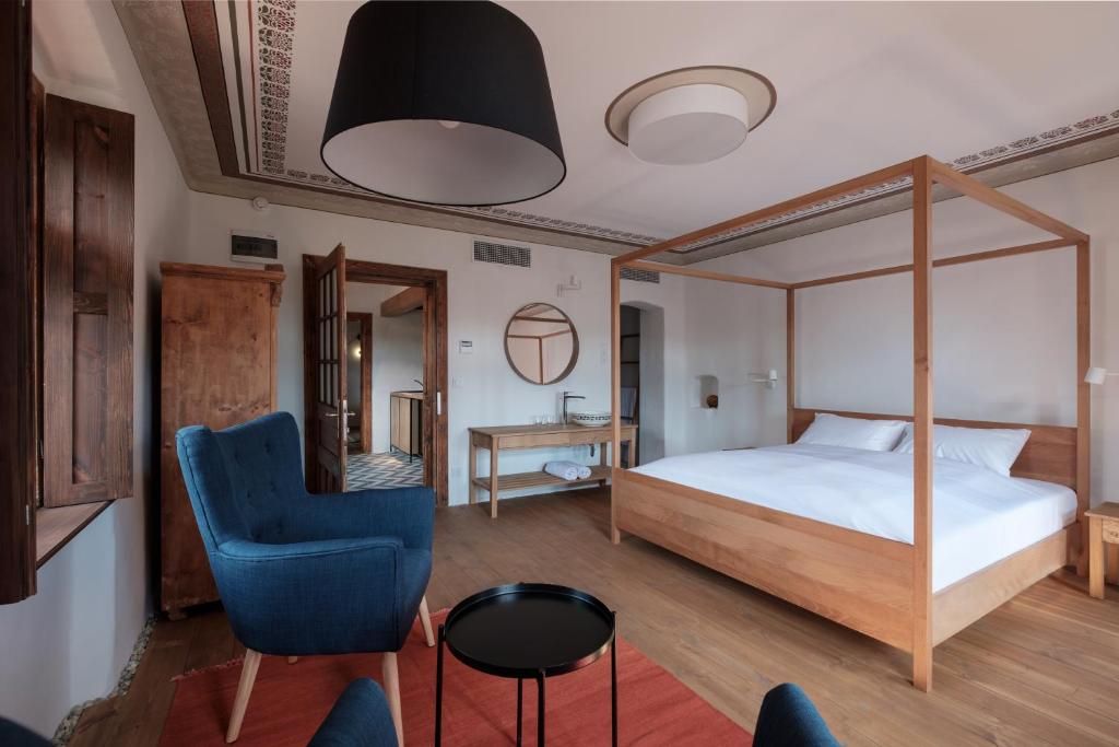 a bedroom with a canopy bed and a blue chair at Almalomb Apartman in Hosszúhétény