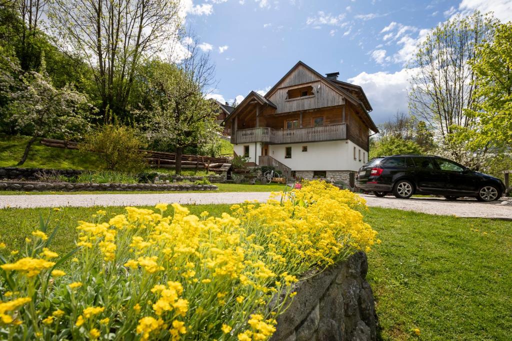 a car parked in front of a house with yellow flowers at Apartments Mlin in Bohinj