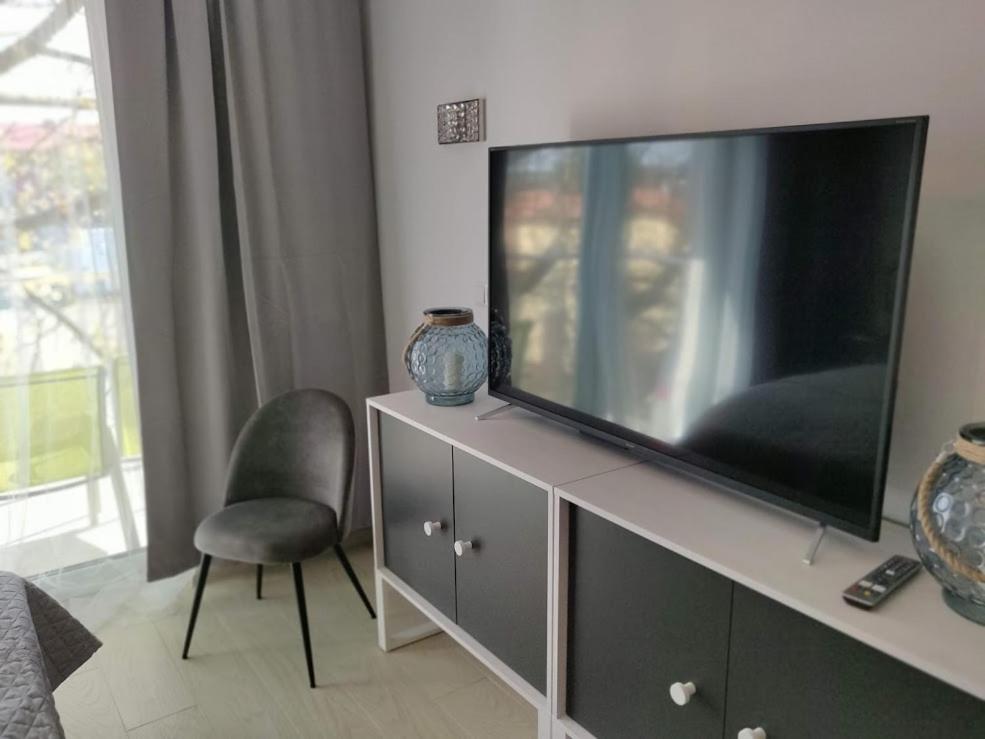 a living room with a large flat screen tv on a cabinet at Apartamenty Hugo Centrum in Słupsk