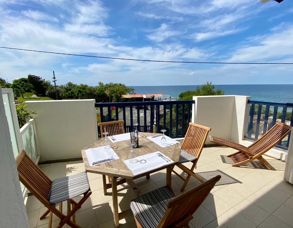 uma mesa e cadeiras numa varanda com o oceano em Bel appartement vue mer - 1er rang front de mer em Saint-Jean-de-Luz