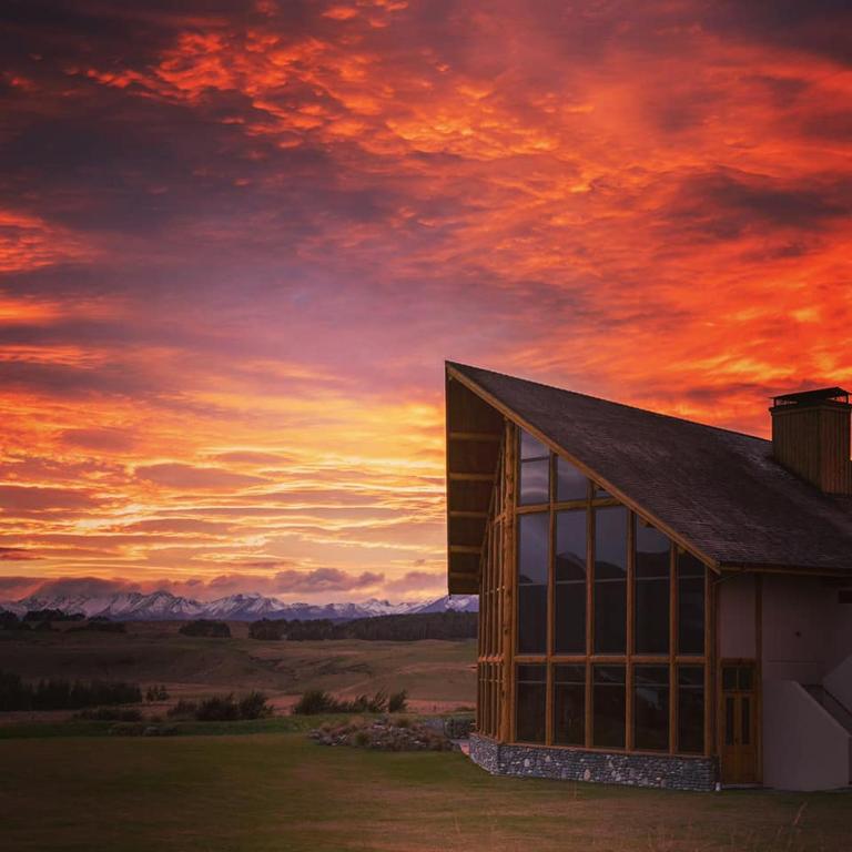 a building with a sunset in the background at Fiordland Lodge in Te Anau