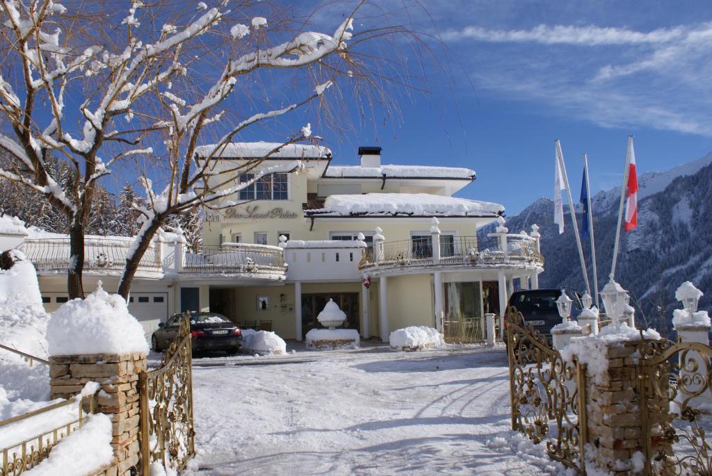 ein großes weißes Haus mit Schnee auf dem Boden in der Unterkunft Das Land-Palais - Your lovely Mountain Hideaway in Mühlwald