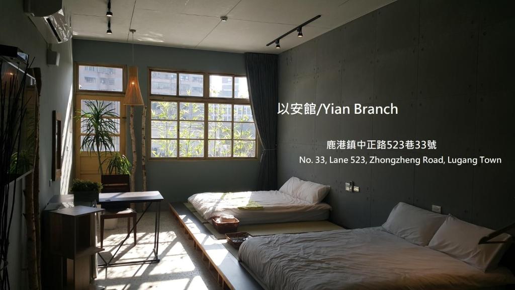 - une chambre avec 2 lits, une table et des fenêtres dans l'établissement Lukang Yian B&B, à Lukang