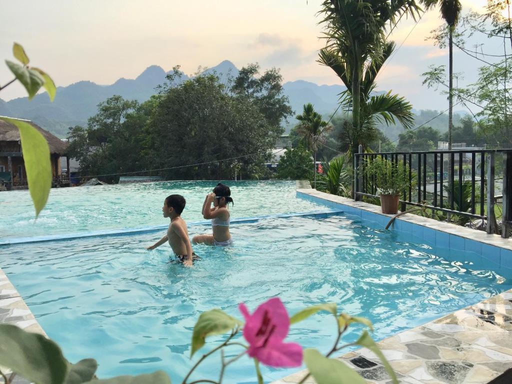 zwei Personen im Pool eines Resorts in der Unterkunft Mai Chau Sunset Boutique Hotel in Mai Châu