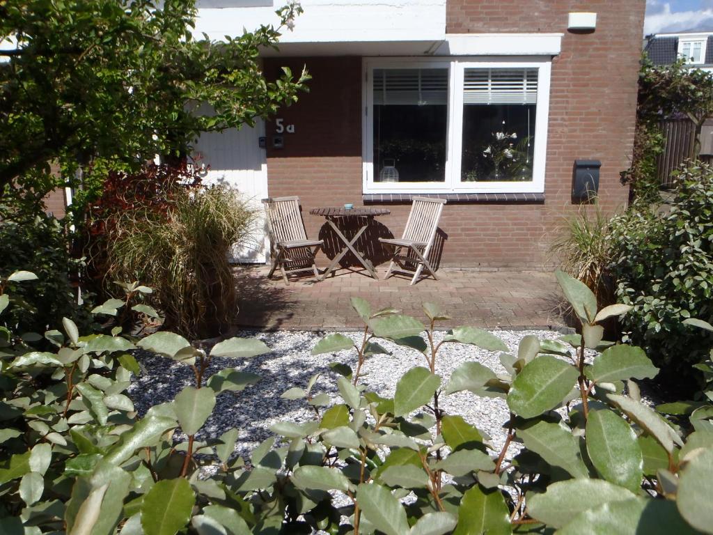 un patio con 2 sillas y una mesa frente a una casa en Holidaytime en Zandvoort