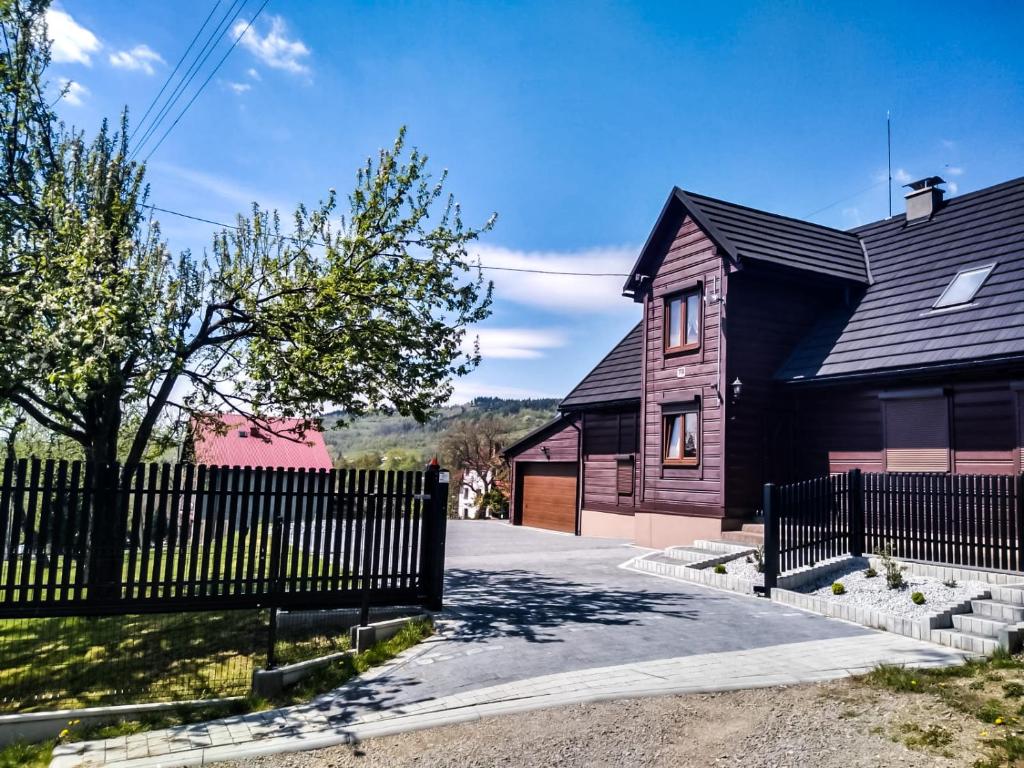 a house with a black fence and a driveway at Beskidzki Domek in Kurów