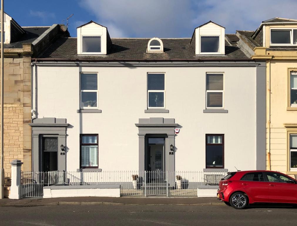 a red car parked in front of a white building at South Beach Apartment in Ardrossan