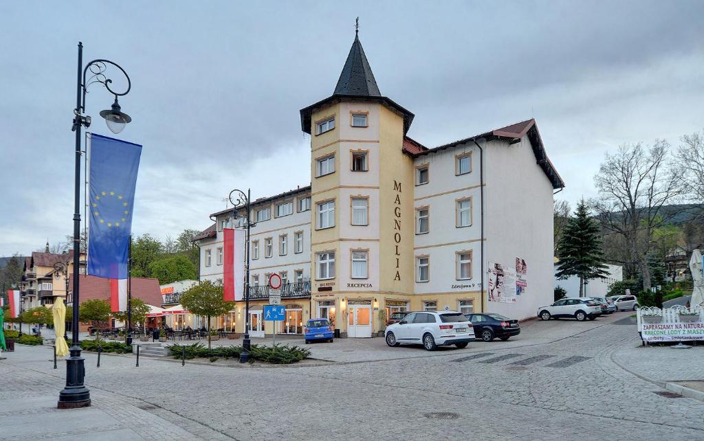 a large building with a tower on a street at Topaz dawniej Magnolia I in Świeradów-Zdrój