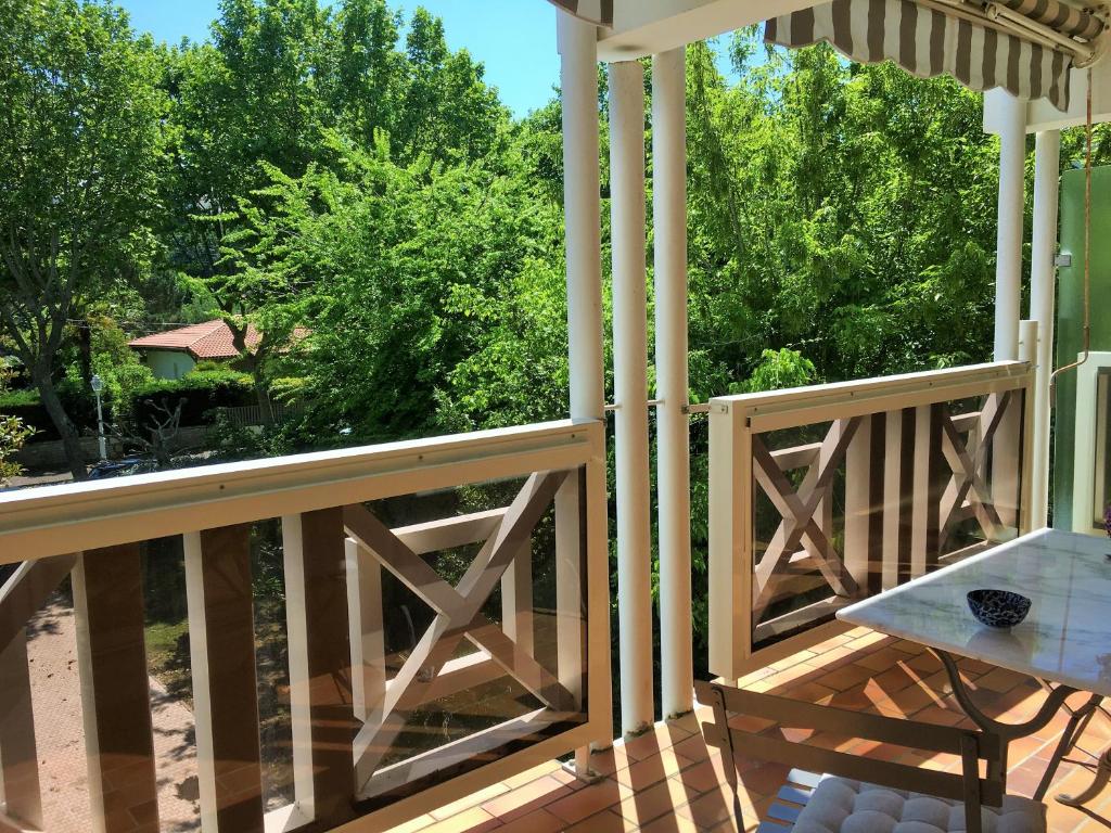 une véranda en bois avec une table et une vue sur les arbres dans l'établissement ST ARNAUD Appartement Calme Parking proche Plage, à Arcachon