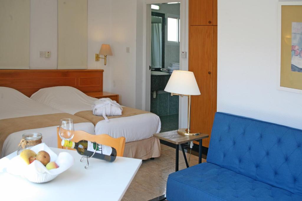 a hotel room with two beds and a bowl of fruit on a table at Chrielka Hotel in Limassol