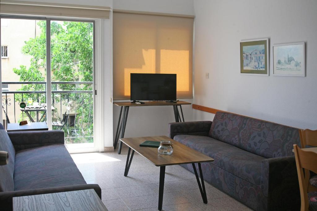 a living room with a couch and a tv at Chrielka Hotel in Limassol